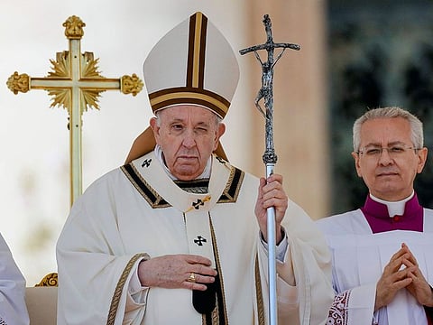 Pope Francis is flanked by his aide Monsignor Diego Ravelli, right, at the end of the Catholic Easter Sunday mass he led in St. Peter's Square at the Vatican, Sunday, April 17, 2022.