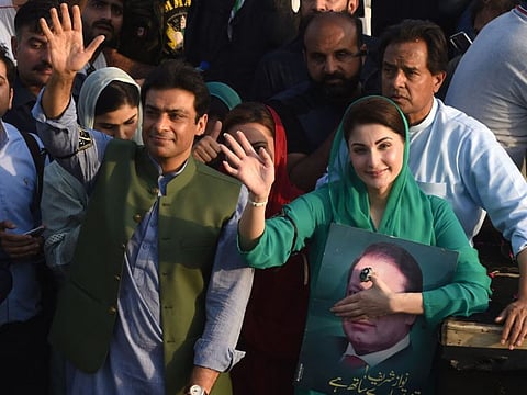 Hamza Shehbaz Sharif waves to his supporters with his cousin Maryam Nawaz standing next to him.