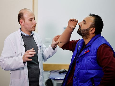 Ahmed Abu Hamda, 36, who lost his right hand in 2007, is shown how to use his newly-installed myoelectric limb at the Sheikh Hamad Bin Khalifa Al Thani Rehabilitation and Prosthetics Hospital in the northern Gaza Strip April 13, 2022.