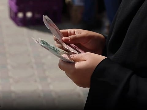 Screengrab of police video depicting beggar counting money after harassing motorists in parking lot