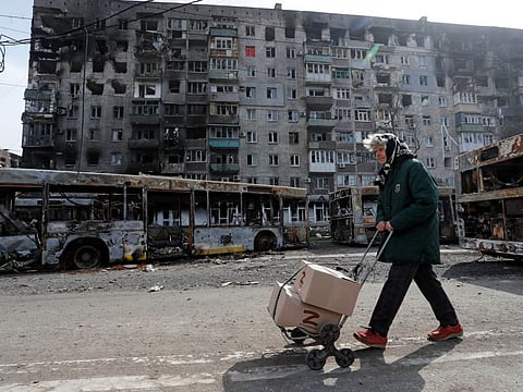 A local resident pulls a cart with humanitarian aid past an apartment building damaged during Ukraine-Russia conflict in the southern port city of Mariupol, on April 19, 2022.