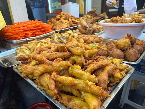 Plates of hot, crunchy samosas (deep-fried savoury snacks with filling), pakoras (fritters) and wadas (deep-fried lentil-based fritters) are up for sale
