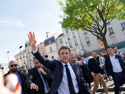 French President Emmanuel Macron, candidate for his re-election in the 2022 French presidential election, waves to residents during a visit in Saint-Denis as he campaigns in Seine-Saint-Denis ahead of the second round of the presidential election, on April 21, 2022.