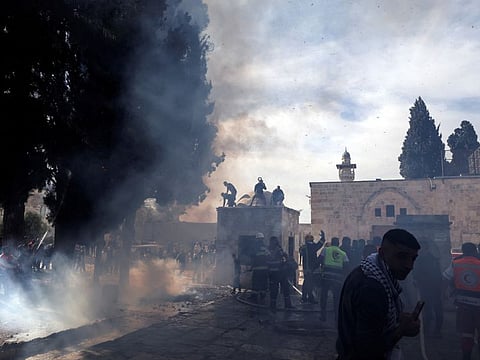 Palestinians put out a fire following a clash with Israeli security forces at the compound that houses Al Aqsa Mosque in Jerusalem's Old City on April 22, 2022.