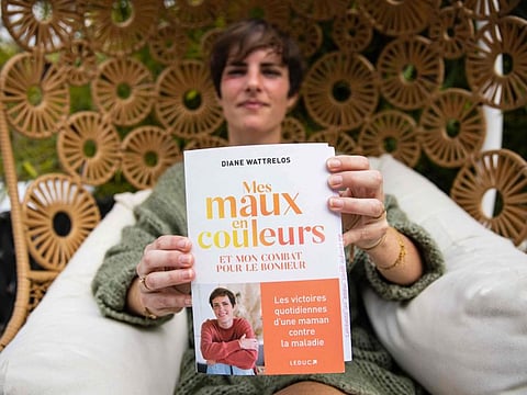 Diane Wattrelos, the 31-year-old mother of two children who wrote "Mes maux en couleurs" (My pain in colours), poses with her book during a photo session at her home in Normandy, northwestern France on April 19, 2022.