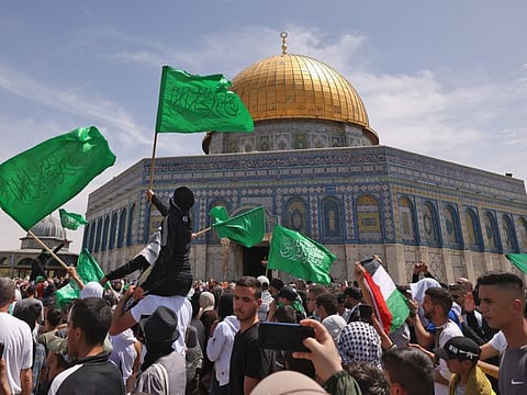 Palestinians wave national and Islamic flags inside Jerusalem's Al Aqsa Mosque complex following prayers of the third Friday of the Muslim holy month of Ramadan, on April 22, 2022.