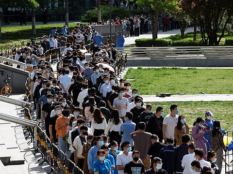 People line up outside a makeshift nucleic acid testing site during a mass testing for COVID-19 in Haidian district of Beijing, on April 26, 2022.