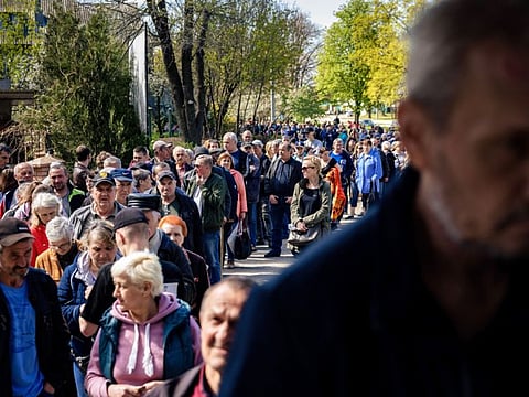 People line up to receive humanitarian aid distributed in a post office in a district of Kharkiv, eastern Ukraine, on April 26, 2022.