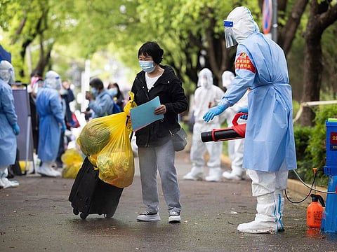 A villager carrying baggage is disinfected as she returns home after being quarantined due to local COVID cases found in Lianqin Village of Beicai Town in Pudong New Area, Shanghai.