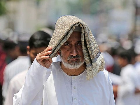 A man covers his head to protect himself from the heat as he leaves after offering prayers on the last Friday of Ramadan at Mecca mosque in Hyderabad, India, Friday, April 29, 2022.