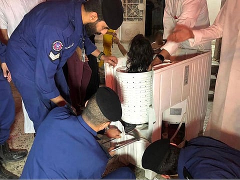 Kuwaiti Fire Force officials trying to pull out the girl from a washing machine.
