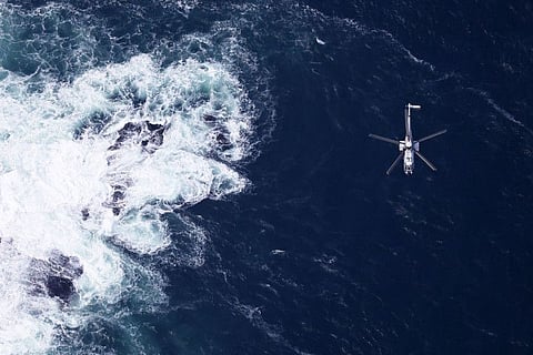 This aerial view from a Jiji Press helicopter shows a Japan Coast Guard helicopter searching near the coast of the northern Japanese island of Hokkaido on April 29, 2022, where a distress signal was made by the sightseeing boat "Kazu 1" on April 23.