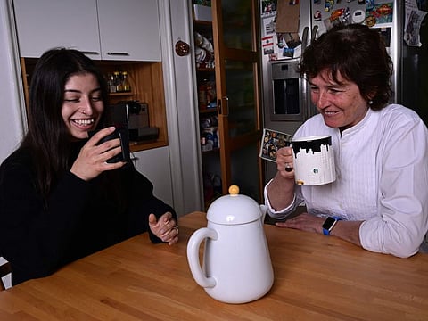 20-years-old Ukrainian refugee Yana Alieva (L), from Kharkiv, is pictured in Milan on April 26, 2022 drinks tea with her Italian adoptive mother Carla Marini in the home of the family which hosts her.
