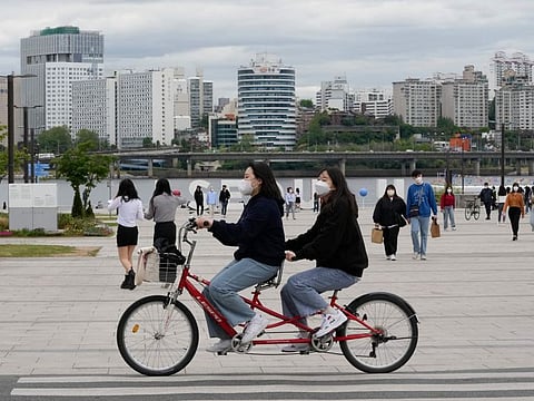 Women wearing face masks ride a bicycle at a park in Seoul, South Korea, Friday, April 29, 2022.