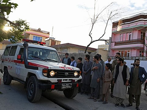 Onlookers stand next to an ambulance carrying victims near the site of a blast in Kabul on April 29, 2022.