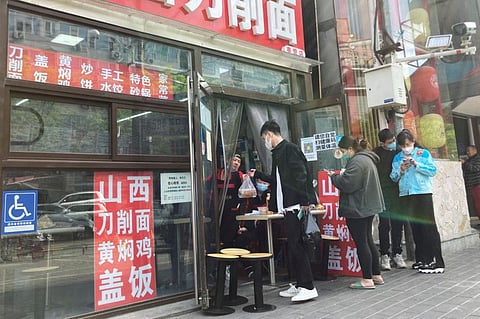 A staff member passes food to a customer at an entrance of a restaurant after the government banned restaurant dining during the Labour Day holiday, to prevent the spread of the coronavirus disease amid the outbreak, in Chaoyang district of Beijing, China May 1, 2022.