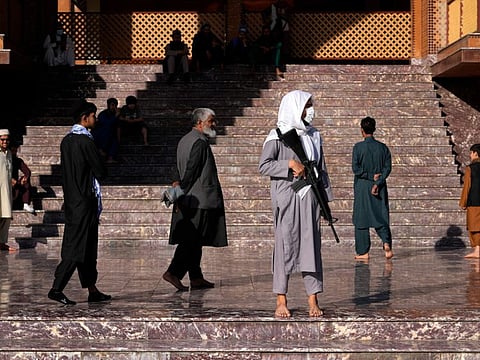 A Taliban fighter stands guard in a mosque at the first day of Eid Al Fitr in Kabul, Afghanistan, Sunday, May 1, 2022.