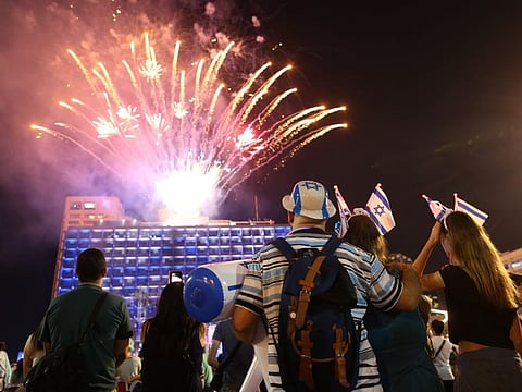 Israelis look at a fireworks show during Israel's 70th Independence Day celebrations at Rabin square in Tel Aviv, Israel.