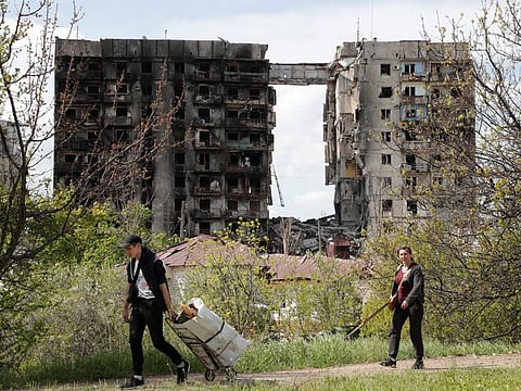 People walk near a residential building destroyed during Ukraine-Russia conflict in the southern port city of Mariupol.