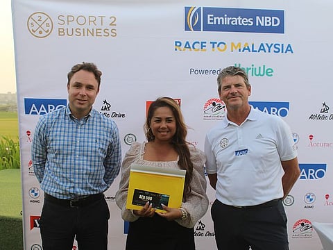 Russell Yeomans (right, Sport2Business) and Lloyd Walton (left, SBGC) present the winner's prize to Division 5 Winner Ethel Dohilling Ang at Saadiyat Beach Golf Club.