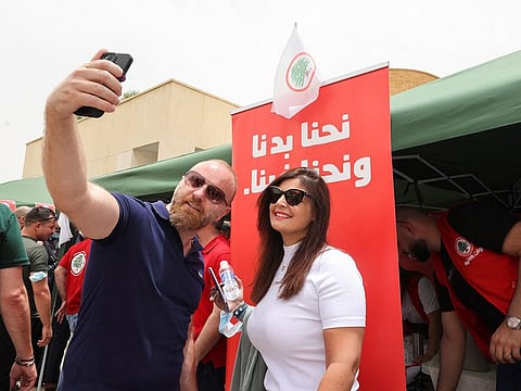 Lebanese expats take selfie in front of an election banner as they arrive to cast their vote in parliamentary elections at the Lebanese Embassy in Riyadh on May 6, 2022.