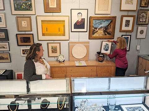 Elizabeth Haynie Wainstein, right, hangs up a piece of modern art belonging to the late Justice Ruth Bader Ginsburg inside Potomack Company Auctions in Old Town Alexandria on Monday April 11, 2022.