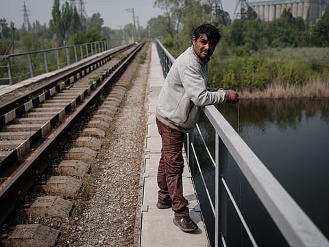 Artur Cherepovskiy, 32, tries to catch fishes from a railway bridge over a river in Slovyansk, eastern Ukraine, on May 8, 2022, amid the Russian attack of Ukraine.