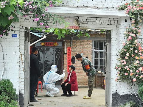 A medical worker taking a swab sample from a resident who can't go out conveniently to be tested for the COVID-19 at her home in Xiayi in China's central Henan province.