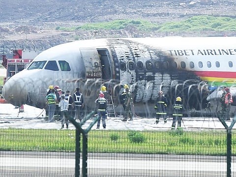 Firefighters check a plane which caught fire after veering off the runway with all passengers and crew evacuated safely, in China's southwestern Chongqing on May 12, 2022.