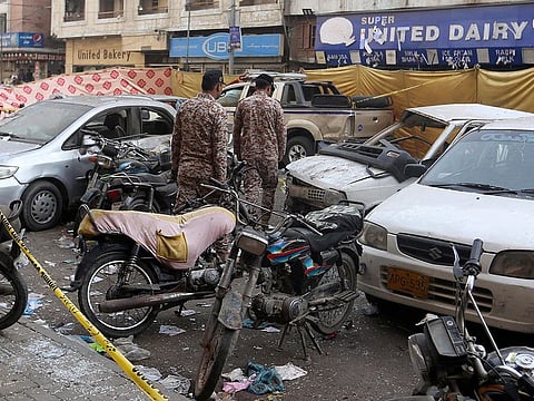 Pakistani paramilitary soldiers examine the cordon-off site of Thursday’s night bomb explosion, in Karachi, on  May 13, 2022.