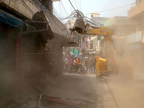A bulldozer demolishes the illegally constructed structures during the anti-encroachment drive by Municipal Corporation (MC), at Khyala Road, in New Delhi on Friday, May 13, 2022.