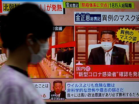 North Korean leader Kim Jong Un, wearing a face mask, appears in a TV news programme.