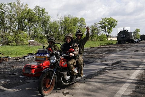 Ukrainian servicemen ride a motorcycle on the road which connects Kharkiv and a village recently retook by the Ukrainian Army, amid Russia's attack on Ukraine, near Kharkiv, Ukraine, May 13, 2022.