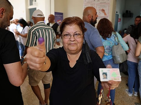 A Lebanese woman shows her ink-stained finger at a polling station after voting for the parliamentary election in the town of Jounieh, north of the capital Beirut, on May 15, 2022.
