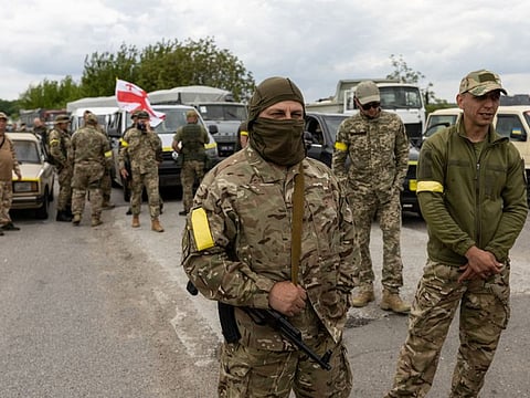 Ukrainian soldiers and volunteers from territorial defense forces pause on the road as the convoy makes a stop on its way to the eastern front, near Oleksandriya, Ukraine May 15, 2022.