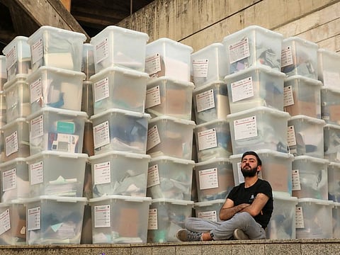 An electoral worker sits next to boxes as Lebanese await the official election results for the rest of the districts in Lebanon's parliamentary election, at the Justice Palace in Jdeideh on May 16, 2022.