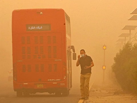 A commuter waits to cross amid a heavy sandstorm in Kuwait City on May 16, 2022.