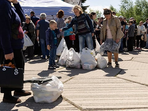 Displaced people from eastern Ukraine wait in line to receive bags with groceries donated by World Central Kitchen, in Mahdalynivka, outside Dnipro, Ukraine, on May 13, 2022.