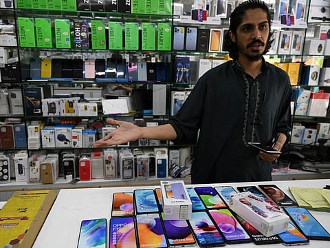 A shopkeeper deals with customer at his mobile shop in Islamabad on May 20, 2022. Pakistans new government has banned the import of luxury items including cars and mobile phones in an austerity move to help boost the country's faltering economy.