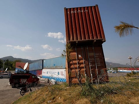 Police officers stand guard next to shipping containers placed by authorities to block a road leading to important government buildings in an attempt to foil a planned rally by Pakistan's key opposition party, in Islamabad on May 24, 2022.