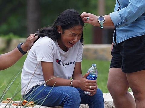 A girl cries, comforted by two adults, outside the Willie de Leon Civic Center where grief counseling will be offered in Uvalde, Texas, on May 24, 2022. - A teenage gunman killed 18 young children in a shooting at an elementary school in Texas on Tuesday, in the deadliest US school shooting in years.