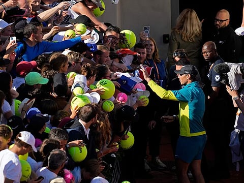 Spain's Rafael Nadal gestures to fans to stay calm as they crush each other lunging forward when trying to get an autograph after his win in the third round of the French Open.