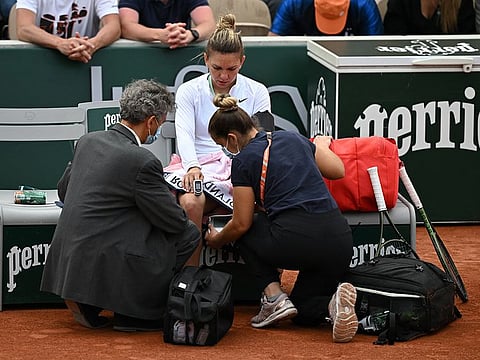 Romania's Simona Halep receives medical attention after getting an on-court panic attack during her second round match against China's Qinwen Zheng on Thursday.