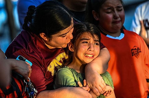 Gabriella Uriegas, a soccer teammate of Tess Mata who died in the shooting, cries while holding her mother Geneva Uriegas as they visit a makeshift memorial outside the Uvalde County Courthouse in Texas on May 26, 2022.