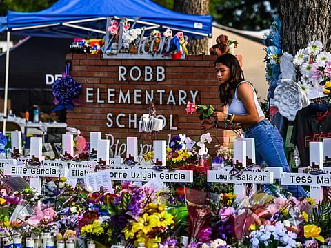 A girl lays flowers at a makeshift memorial at Robb Elementary School in Uvalde, Texas, on May 28, 2022.