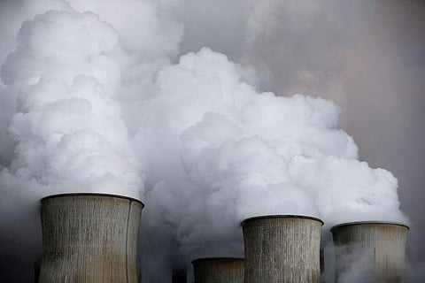 Steam rises from the cooling towers of a coal power plant.