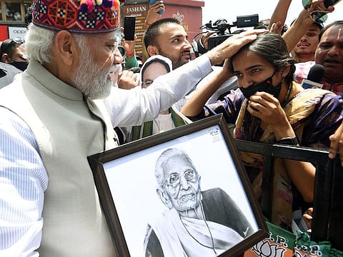 Prime Minister Narendra Modi blesses the girl after receiving from her a handmade portrait of his mother.