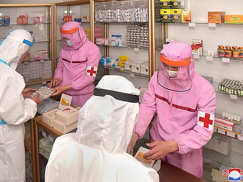 This picture taken and released from North Korea's official Korean Central News Agency (KCNA) on May 31, 2022 shows Korean People's Army medical personnel in protective clothing supplying medicines at a pharmacy in Pyongyang.
