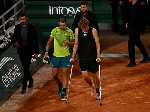 Germany's Alexander Zverev (right) walks with crutches on the court after being injured during his men's semi-final singles match against Spain's Rafael Nadal on day thirteen of the Roland-Garros Open tennis tournament at the Court Philippe-Chatrier in Paris.