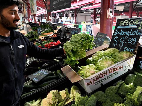 Syed Hyder from a stall at Melbourne's Queen Victoria Market adjusts a display of iceberg lettuce on June 7, 2022, with the local price soaring by as much as 300 per cent in recent months.